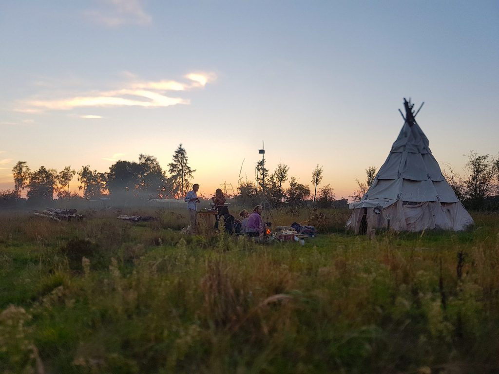 Kampvuur bij de tipi en de ondergaande zon op Natuurkampeerterrein Klein Schoor